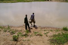 Two_boys_collecting_water_from_a_typical_dugout_in_Ghanasco